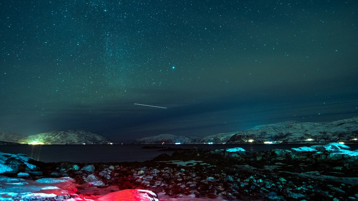 a night sky with stars and a bright red tent in the foreground
